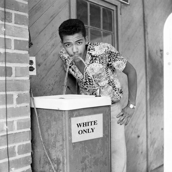 A man drinks from a water fountain labeled 'WHITE ONLY', a moment nearly lost to history.
