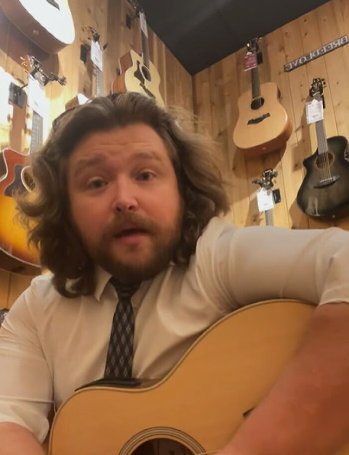 Former Disney heartthrob, an unrecognizable man with long hair and a beard, playing a guitar in a music store.