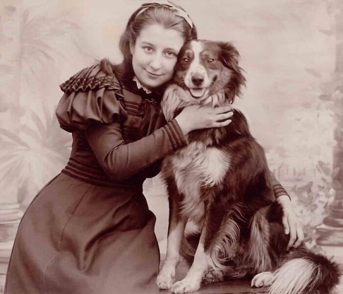 A vintage photo of a woman affectionately hugging a dog, demonstrating animals stealing the spotlight.