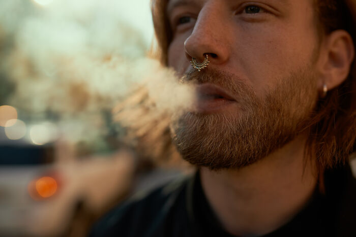 A man exhaling smoke, illustrating things doctors refuse to do for better health.