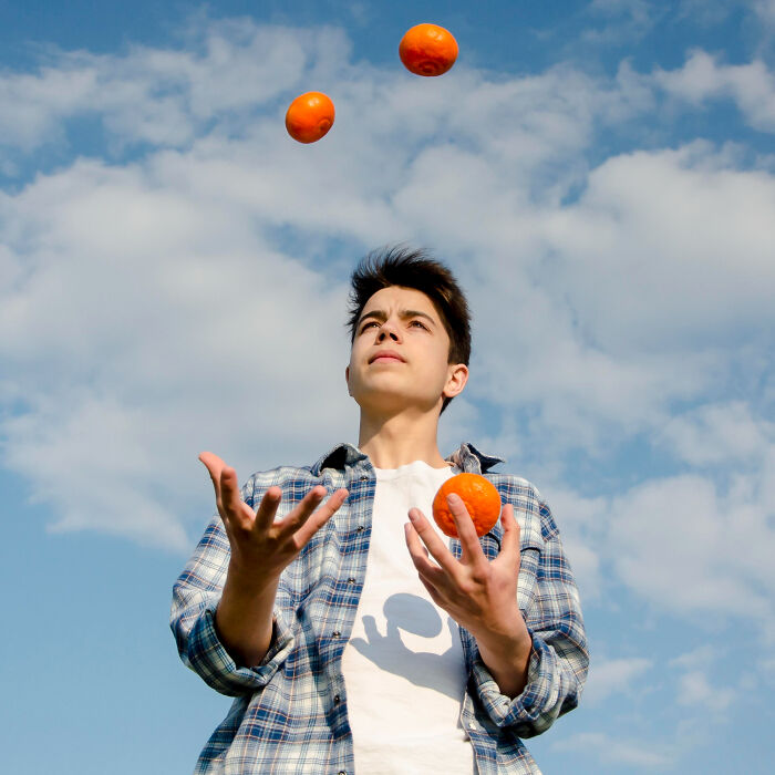 A young man juggling oranges against a blue sky, learning new skills that genuinely changed his life.