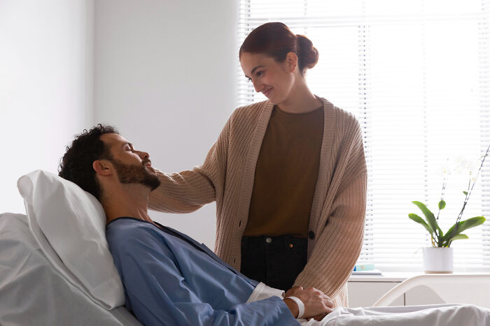 Woman comforting a man in a hospital bed, a challenging situation that can test couples and lead to divorce.
