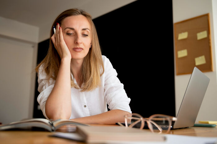 A woman looking tired while studying at her laptop, acquiring new skills that genuinely changed her life.