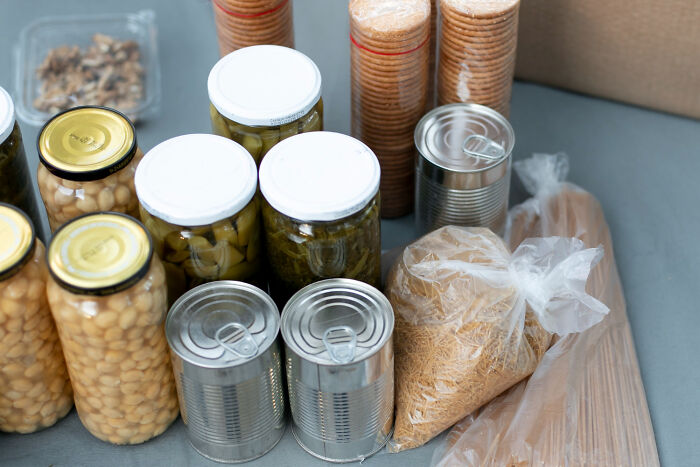 Various canned goods, jars of food, and dry pasta, symbolizing food storage and poverty habits.
