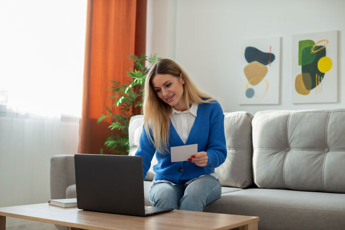A woman on a couch looking at a small card, hinting at a secret she'd never confess.