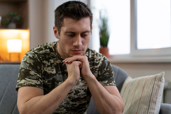 A thoughtful man in a military uniform looks down, hinting at a secret he would never confess.