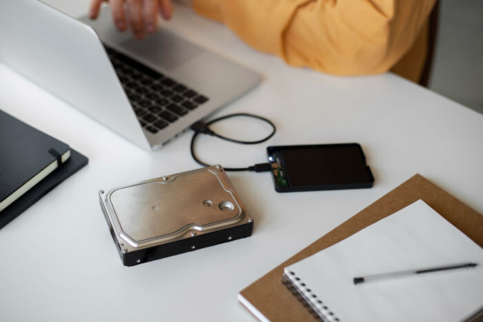 A person using a laptop connected to a hard drive, potentially related to employee data or reasons for being fired.