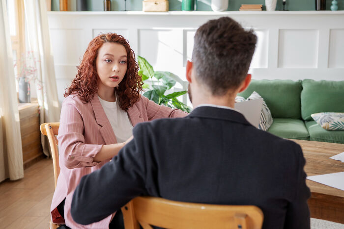 A woman talks to her therapist, sharing her experience during a therapy session.