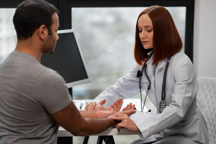 A female doctor examining a male patient's hand, highlighting things doctors refuse to do.