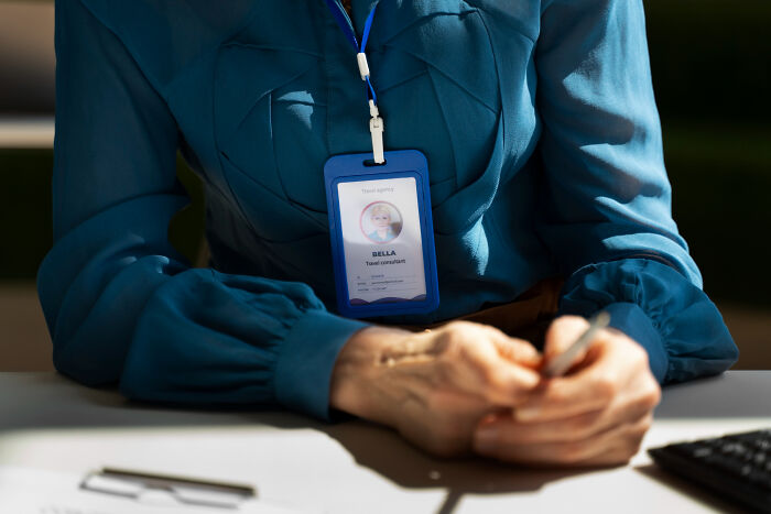 A woman wearing a blue blouse and a badge for travel consultant Bella. Doctors refuse to do some things.