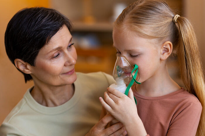 A caring woman assists a young girl with an oxygen mask, revealing a difficult health secret.