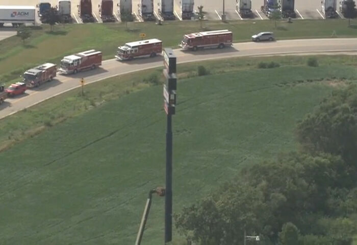 Several emergency vehicles on a road near a tall sign where an electrician got stuck 130ft high.