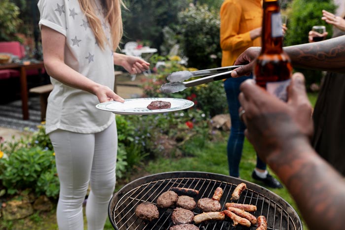 People at a backyard barbecue, where one person is grilling, symbolizing shared spaces and dumb work rules.
