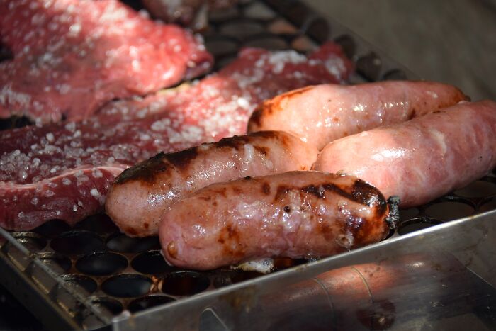 Sausages and cuts of meat on a grill, reflecting on grilling habits and the perception of healthy eating choices.