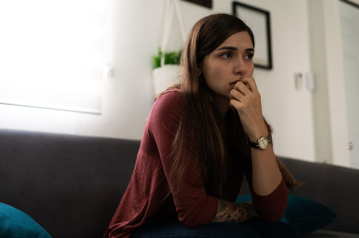 A woman on a couch looking distraught, showing her distress after uncovering her boyfriend's family's cruel plan. A woman on a couch looking distraught, showing her distress after uncovering her boyfriend's family's cruel plan.
