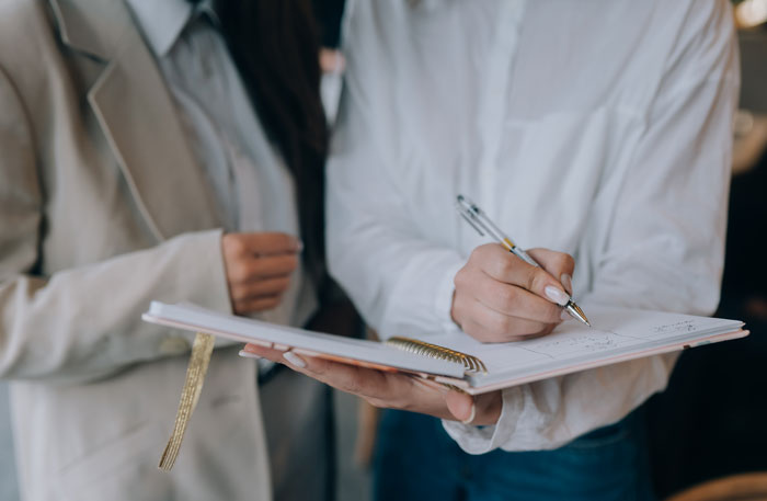 A bride writing in a planner, frustrated with her future mother-in-law trying to take over the wedding. A bride writing in a planner, frustrated with her future mother-in-law trying to take over the wedding.