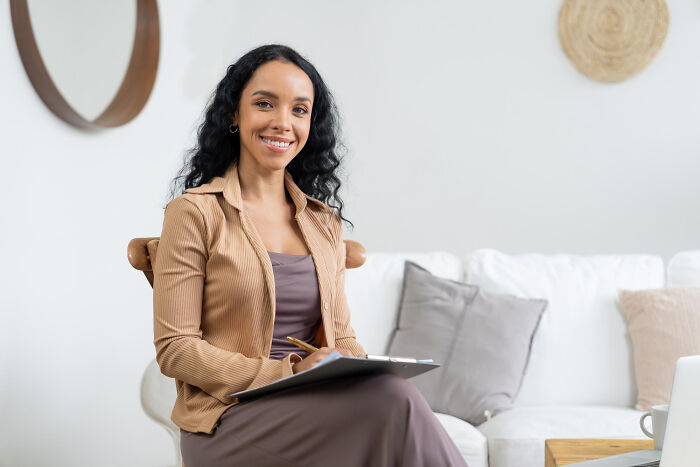 A smiling female therapist holds a clipboard, ready to discuss client experiences and the reasons for ending therapy.