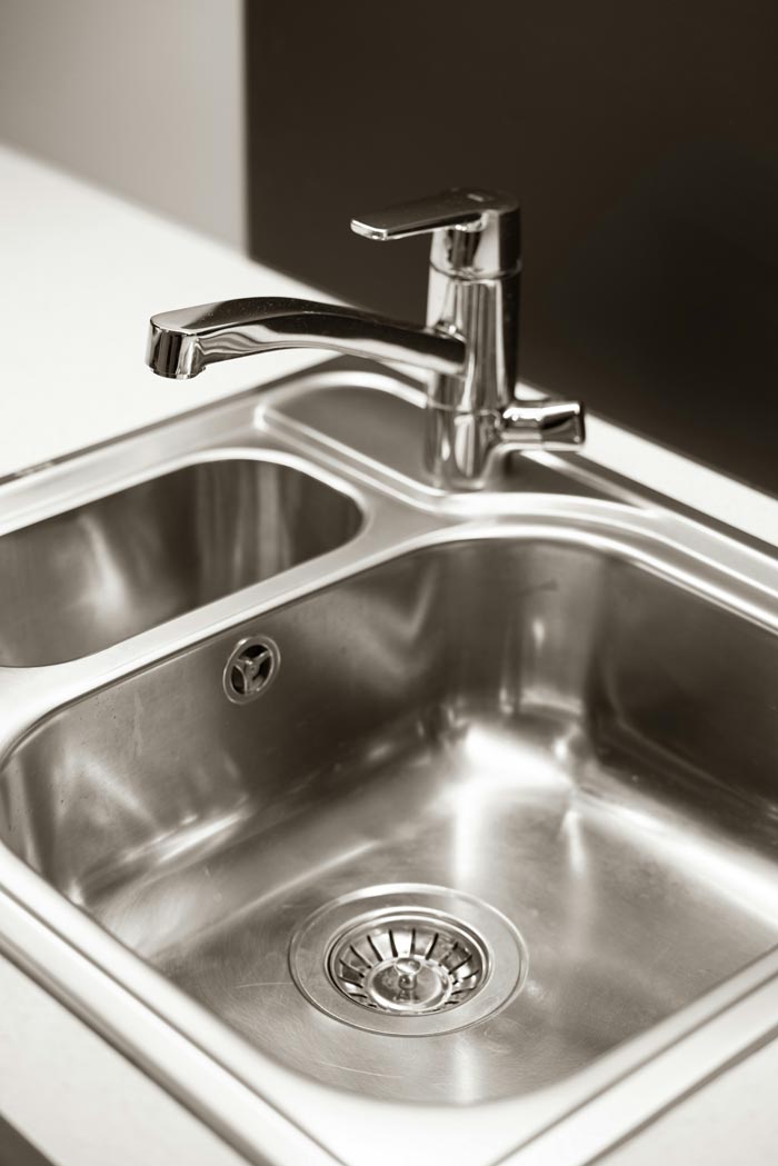 A shining stainless steel kitchen sink and faucet, reflecting on dumb work rules.