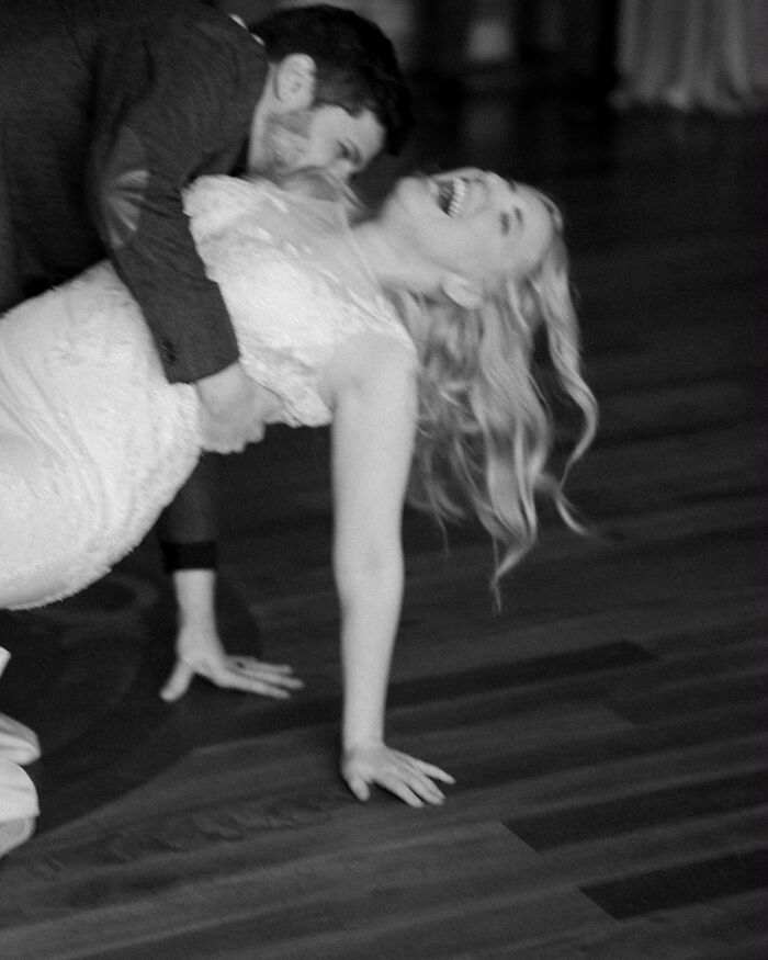 Iconic, funny wedding photo in black and white of a groom dipping his bride, who is laughing joyfully.
