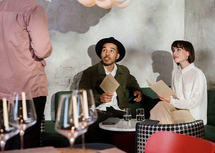 A couple looking surprised and attentive while on a first date in a restaurant setting.