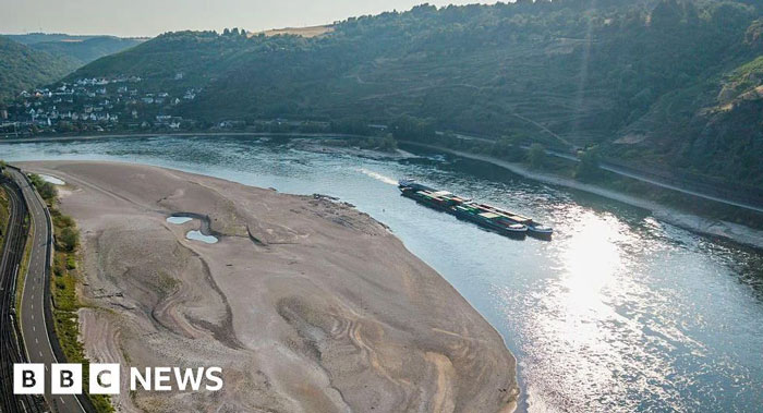Barge on a low river, with a wide dry bank, depicting summer melting and ruined waterways.