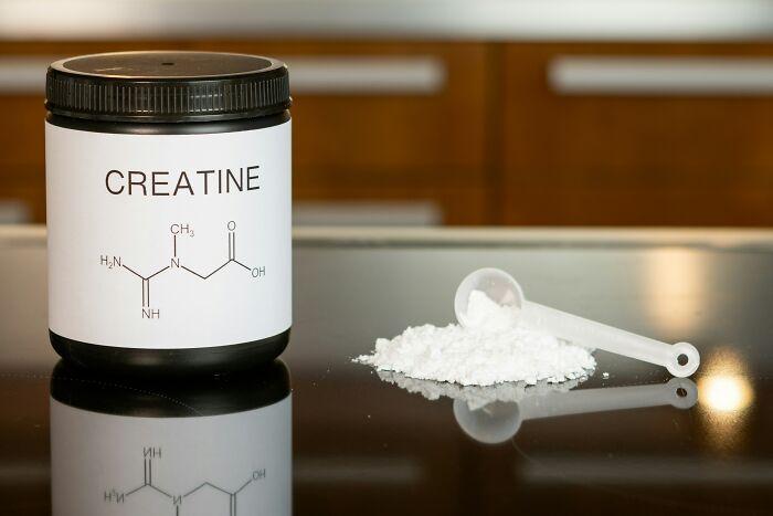A container of creatine next to a scoop of powder, representing a healthy habit many people glorify.