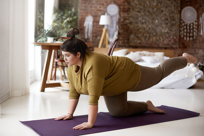 A woman doing yoga on a mat in a bedroom, balancing on hands and knees. Doctors refuse to do certain things.