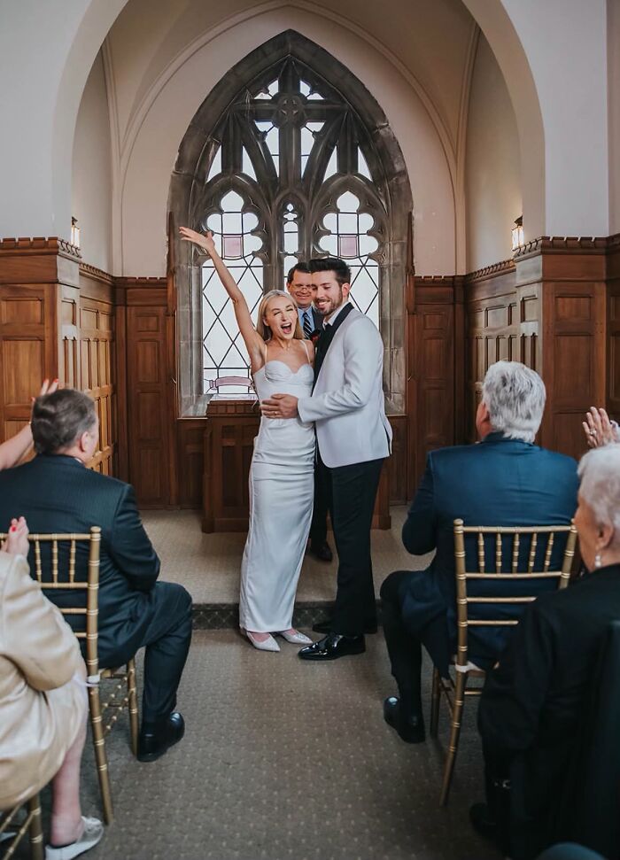 A newlywed couple celebrates their wedding with arms raised in a church, a funny wedding photo.