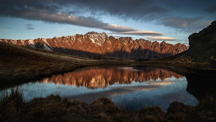 Snow-capped mountains reflecting in a tranquil lake at sunset, a beautiful winning image from the European Photography Awards.