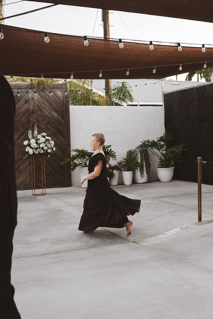 A funny wedding photo of a guest in a black dress running barefoot, capturing an iconic, candid moment.