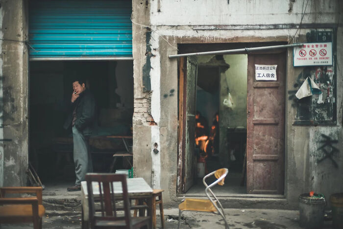 A woman sits amidst rubble, a poignant scene of the world, capturing a winning image for European Photography Awards.