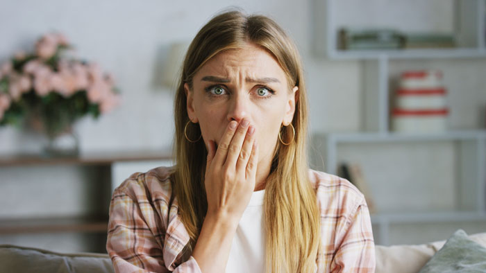 A woman looks shocked and concerned, suspecting her dad is tampering with her dessert, making her mysteriously sick.