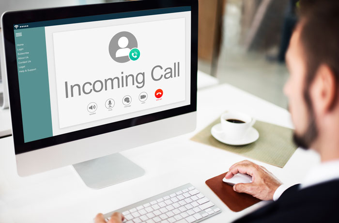 A man on a computer with an incoming call notification, related to a workplace bully and secret recording. A man on a computer with an incoming call notification, related to a workplace bully and secret recording.