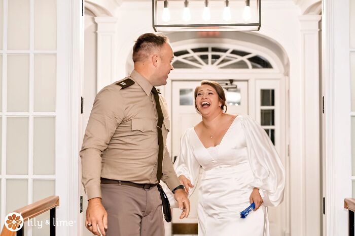 Funny wedding photo of a bride and groom sharing a laugh while walking indoors.