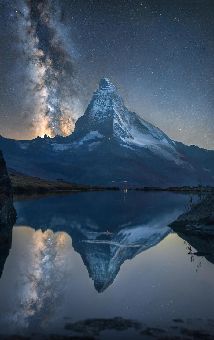 The Matterhorn mountain under a starry night sky, reflecting in a still lake, a stunning European Photography Award-winning image.