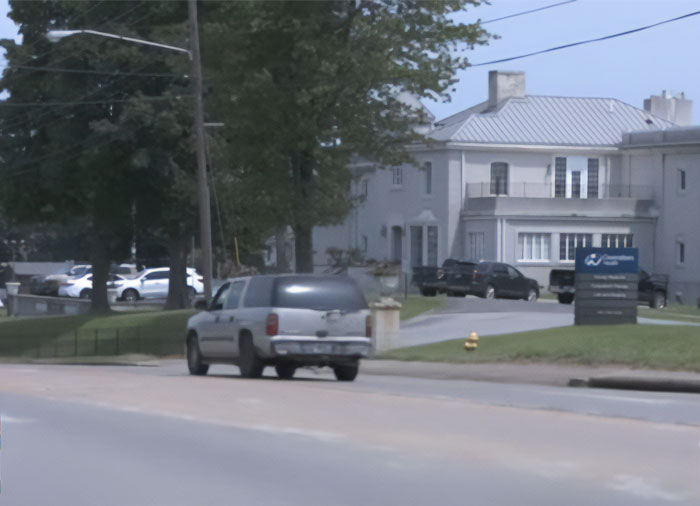A car drives away from a building, relevant to a doctor forgetting a baby granddaughter in a hot car. A car drives away from a building, relevant to a doctor forgetting a baby granddaughter in a hot car.