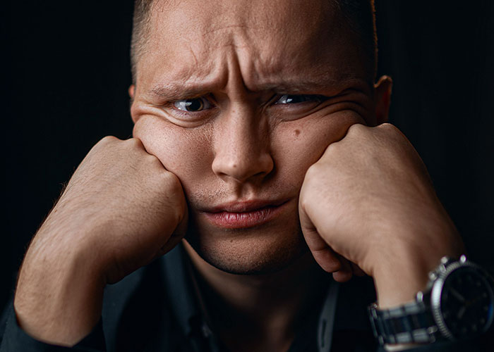 A man with a pained expression, hands pressed against his cheeks, illustrating the feeling of worst first dates.