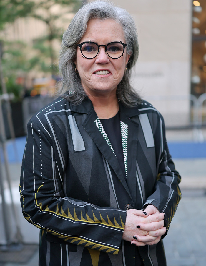 Rosie O'Donnell smiling in a black and gold patterned jacket, discussing Trump rumors.