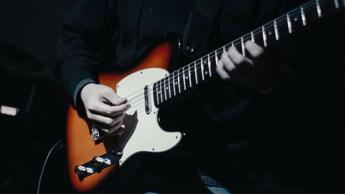 Close-up of a person playing an electric guitar, potentially as an escape from controlling relationship.