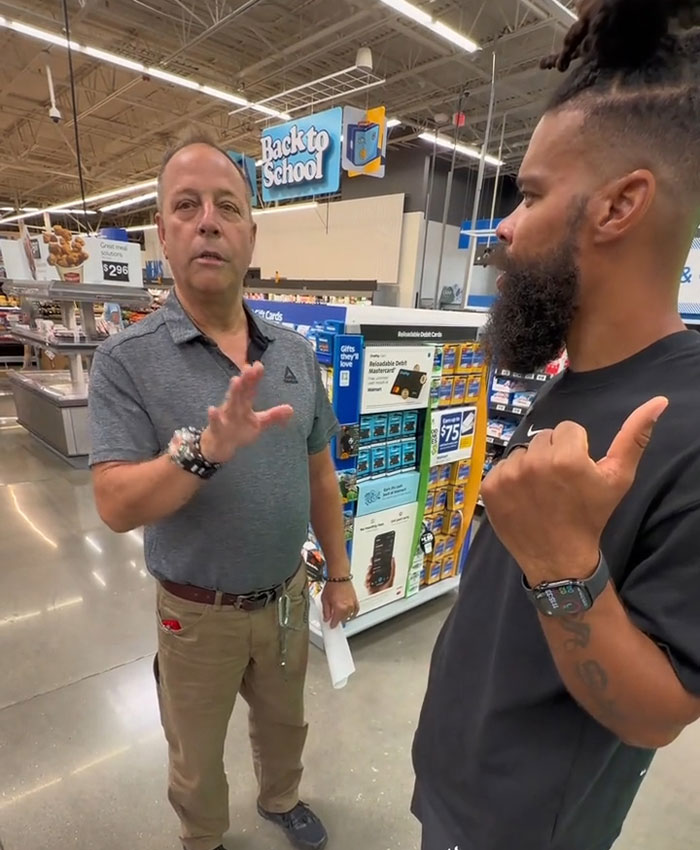An influencer having a conversation with a Walmart employee inside the store, likely discussing the lifetime ban issue.