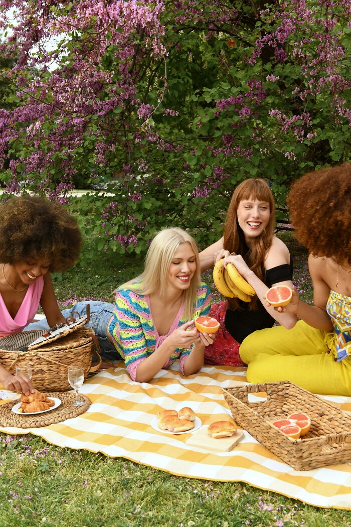 Four women enjoying a picnic under a flowering tree, a contrast to breakup-worthy things partners did.