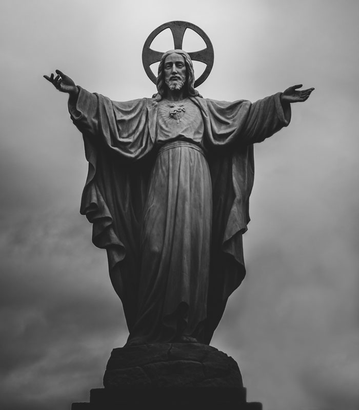 A black and white statue of Jesus with arms outstretched, representing 'Letting Jesus Handle It' for wife material.