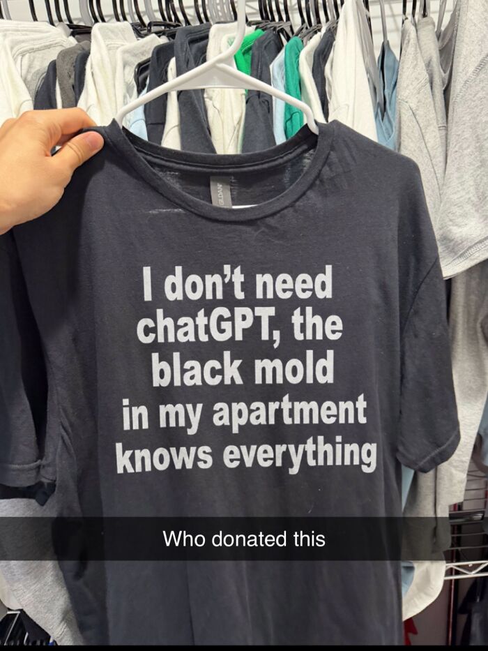 A person holding an iconic shirt that says I don’t need chatGPT, the black mold in my apartment knows everything.