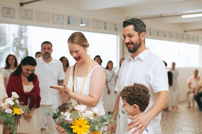 Funny wedding photo of a bride looking at her wedding ring with the groom and a child.