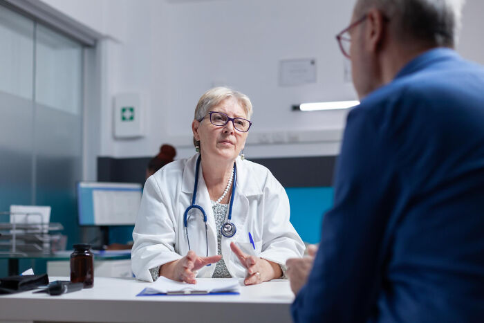 A doctor discusses difficult diagnoses with a patient in a medical office, showing the gravity of the situation.