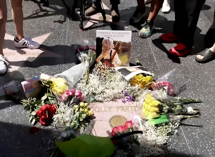 Dolly Parton's Hollywood Walk of Fame star covered in flowers and memorials, honoring her passing.