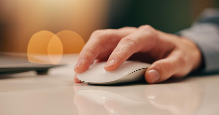 A hand operating a computer mouse, illustrating the digital aspect of shocking employee stories leading to being fired.