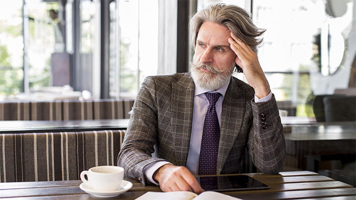 A thoughtful man, realizing his neighbors just want him to pay their bills, sits at a cafe. A thoughtful man, realizing his neighbors just want him to pay their bills, sits at a cafe.