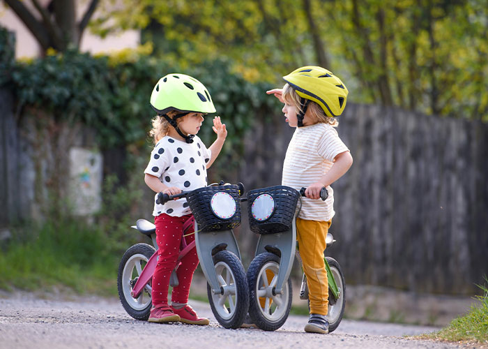Two young children in helmets with their bikes. A doctor lists five things parents should never allow children to do.