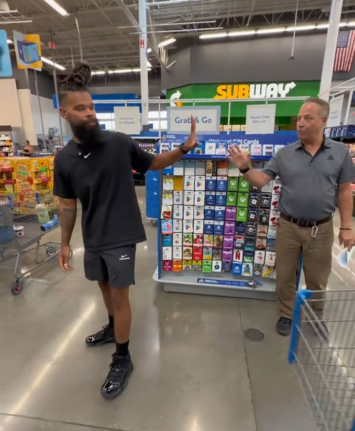 Influencer and a Walmart employee gesturing at each other near a gift card display, amidst the dispute of a lifetime ban.